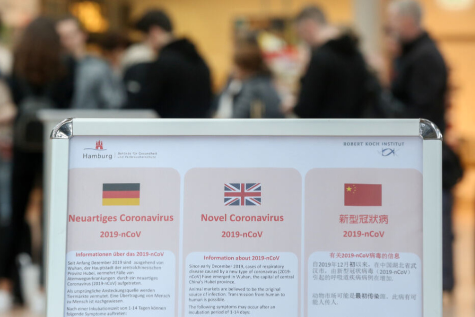 Ein Aufsteller am Hamburger Flughafen informiert in drei Sprachen über das Coronavirus.