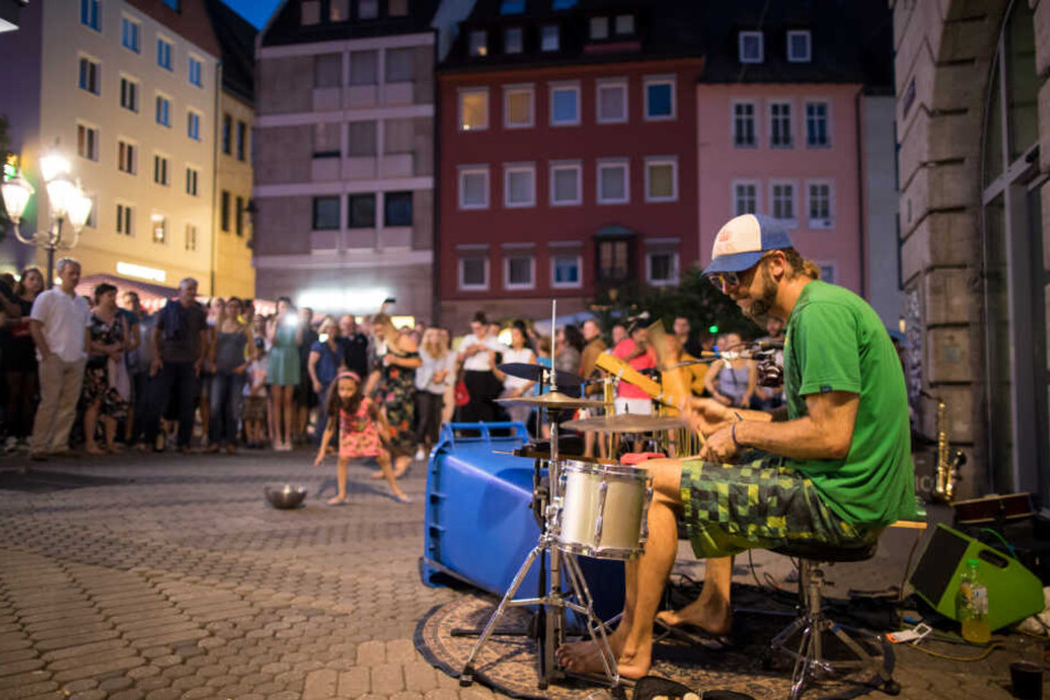 Ein Straßenmusiker spielt beim Nürnberger Bardentreffen auf einem Schlagzeug, das zum Teil aus einer Mülltonne besteht.