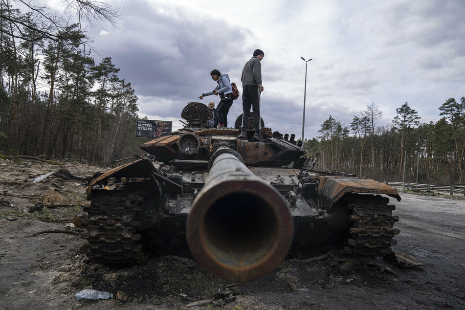 Anwohner stehen auf einem russischen Panzer, der bei Kämpfen zwischen russischen und ukrainischen Streitkräften in einem Außenbezirken von Kiew beschädigt wurde.