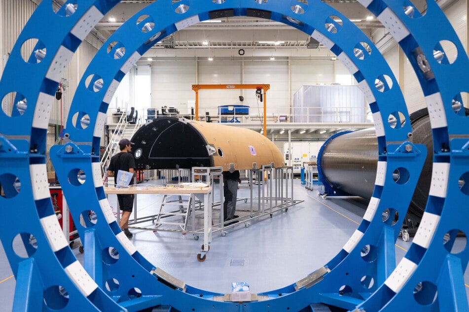 Mitarbeiter des Raumfahrtunternehmens Isar Aerospace fertigen in einer Halle die Verkleidung einer Rakete. Bald soll die erste Test-Version ins All aufbrechen.