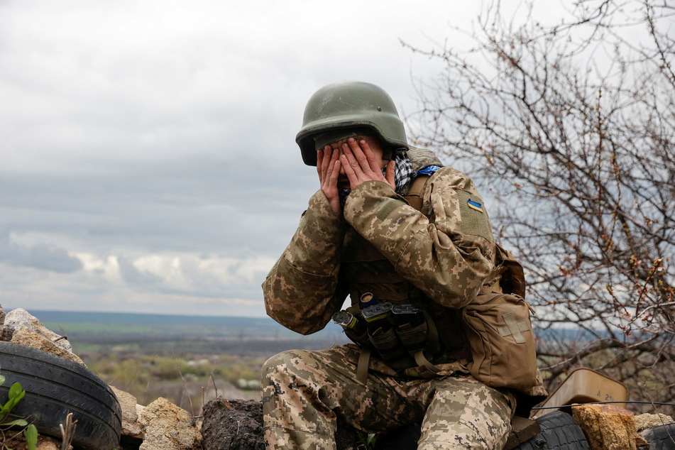 A Ukrainian service member in the Donetsk region covers his face.