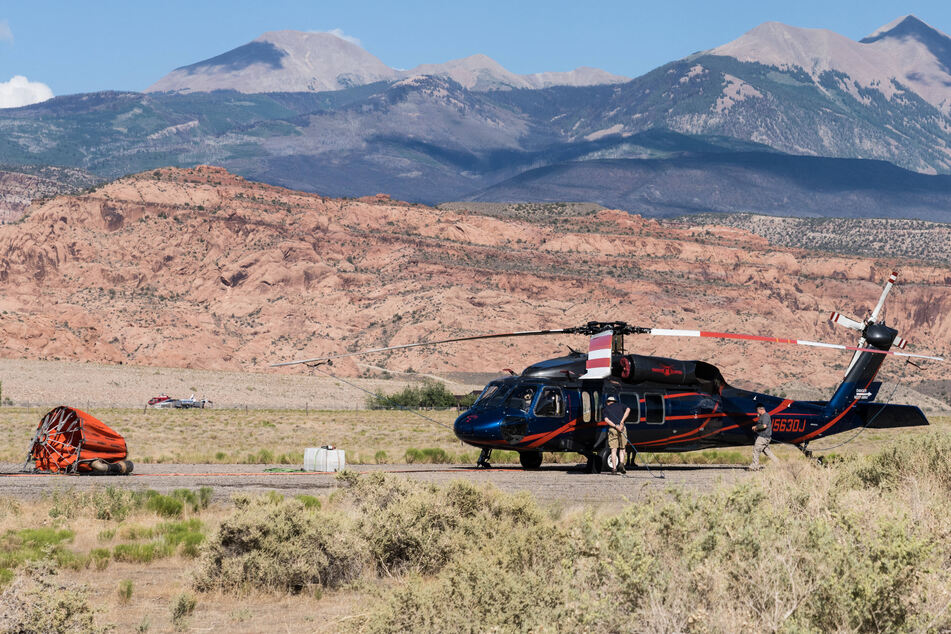 A firefighting crew in Moab, Utah, secures the rotor blades of a Sikorsky UH-60 with a Bambi Bucket helibucket for scooping water and dumping it on fires.