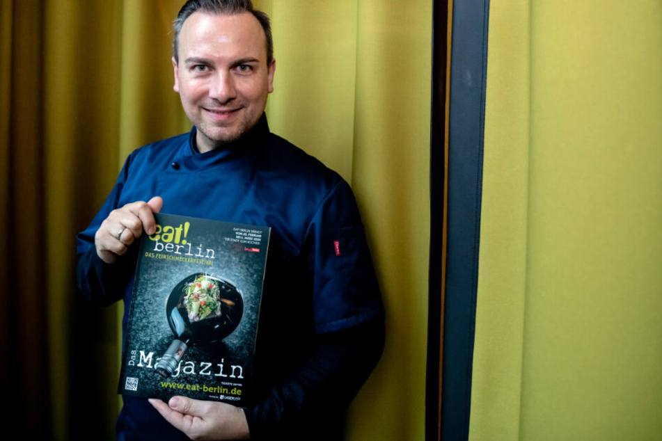 Tim Raue, Koch, hält bei einem Pressetermin anlässlich der Vorstellung des Programms des Feinschmeckerfestivals "eat! Berlin" das Festivalmagazin.
