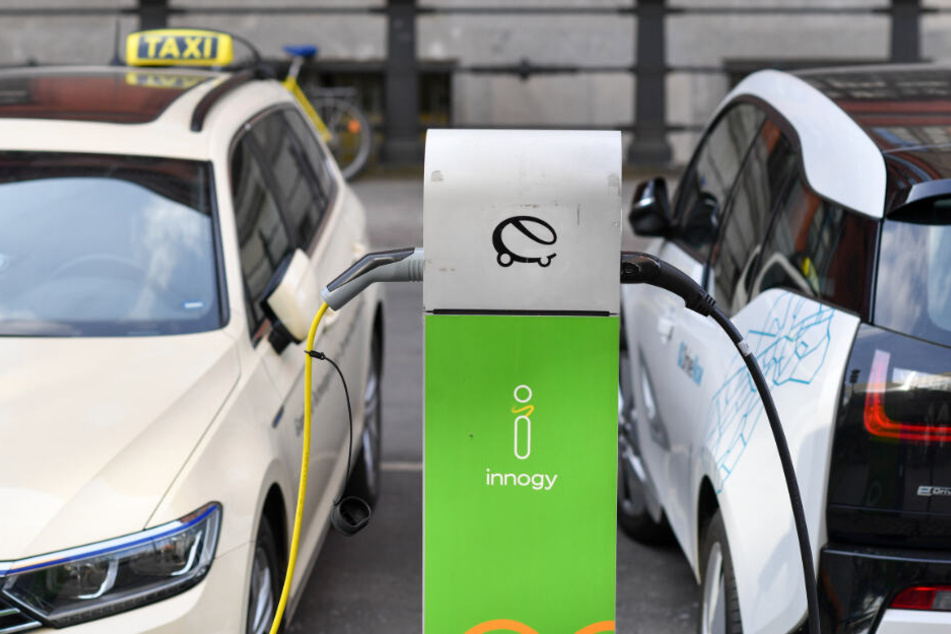 Ein Taxi und ein Carsharing-Fahrzeug werden an einer Ladestation geladen.