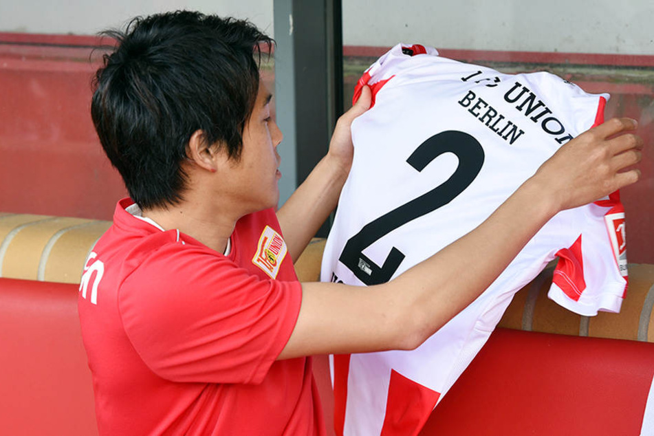Uchida bestaunt sein neues rot-weißes Trikot mit der Rückennummer 2.