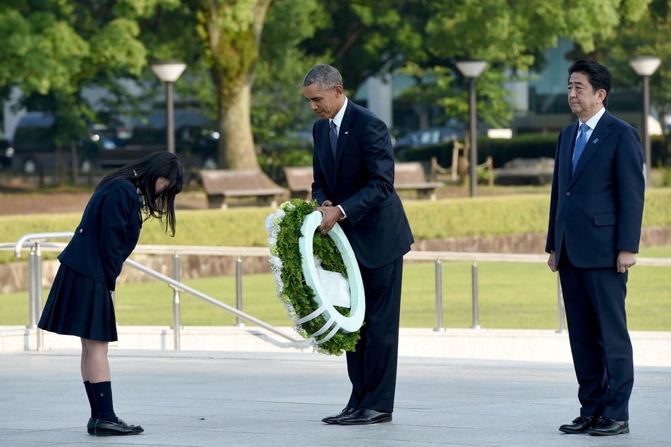 This file photo taken on May 27, 2016 shows US President Barack Obama (C) receiving a wreath from a student (L) beside Japan's Prime Minister Shinzo Abe (R) at the Cenotaph in the Peace Memorial Park in Hiroshima during the US president's historic visit when he became the first sitting US president to come to the city.