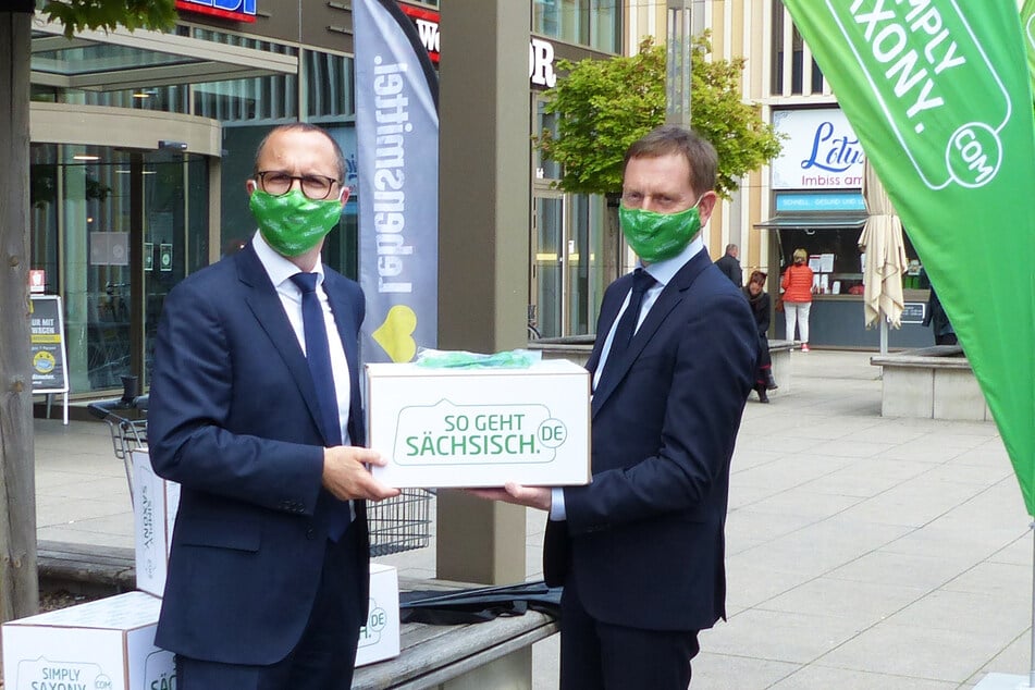 Sachsens Ministerpräsident Michael Kretschmer (r.) übergibt 1000 Mund-Nase-Masken an Toni Kunze, Geschäftsbereichsleiter Expansion der EDEKA Grundstücksgesellschaft Nordbayern-Sachsen-Thüringen mbH.