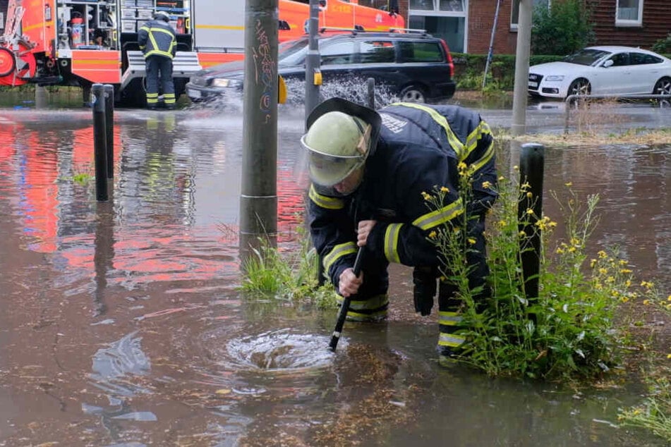 Ein Feuerwehrmann kämpft gegen die Wassermassen an einer Kreuzung.