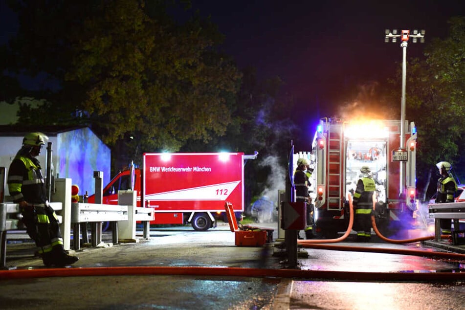 Einsatzkräfte der BMW-Werksfeuerwehr stehen bei einem Einsatz auf dem Werksgelände bei ihren Fahrzeugen.