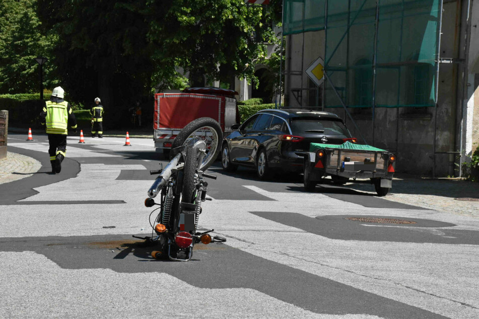 Das Moped fuhr gegen den grünen Fahrzeug-Anhänger (r.) und blieb auf dem Lenker liegen.