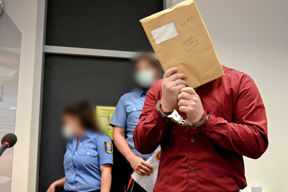 Der Angeklagte betritt im August in Handschellen den Gerichtssaal des Landgerichts und verbirgt sein Gesicht.