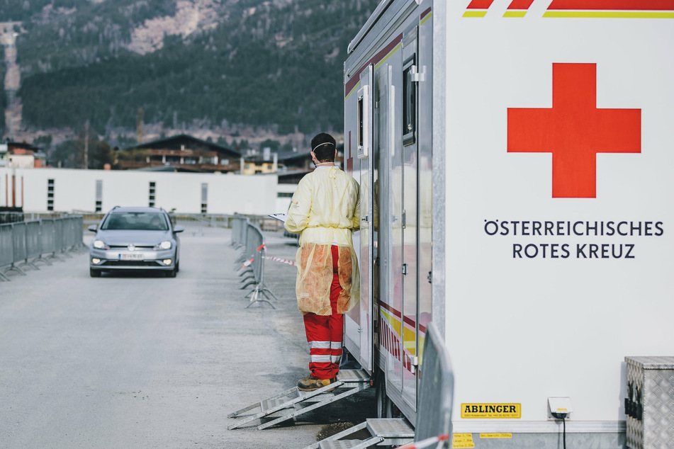 Ein Mitarbeiter des Roten Kreuzes wartet auf Personen mit Erkrankungsverdacht in der Drive-In Teststation für Corona-Verdachtsfälle im Stadtteil Schüttdorf in Zell am See. 