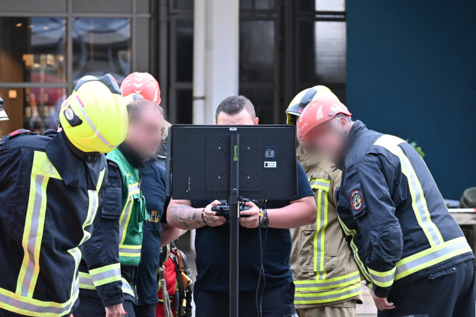 Feuerwehrleute betrachten am Monitor die Suche nach der Drohne.