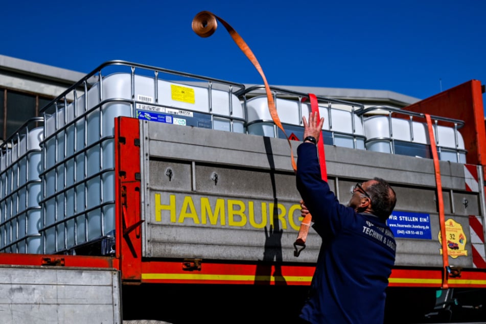 Ein Mitarbeiter der Feuerwehr verpackt auf dem Betriebsgelände der Beierdorf AG Paletten mit Desinfektionsmitteln auf einem Einsatzfahrzeug. 