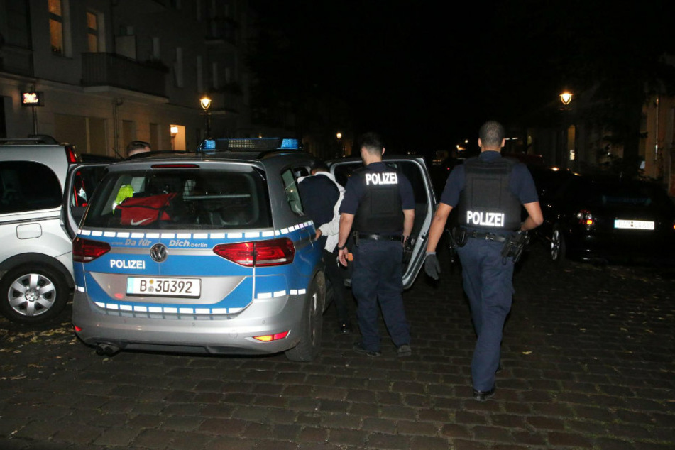 Polizisten führen einen der Tatverdächtigen ab.