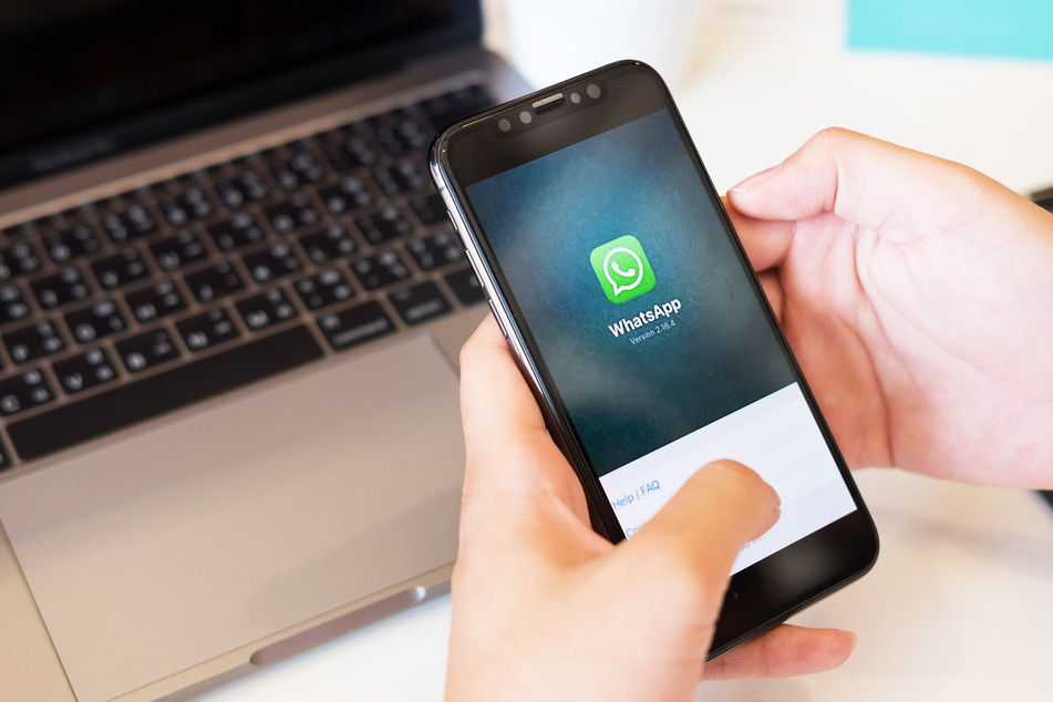 Ein Mann hält ein Smartphone mit der geöffneten WhatsApp-Anwendung.