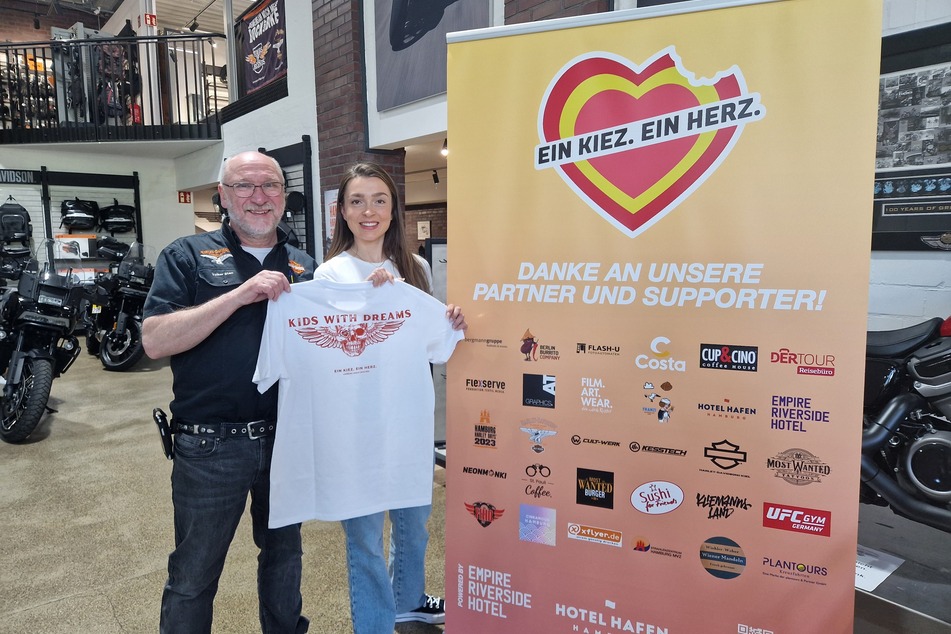 Volker und Charlotte von "Ein Kiez. Ein Herz" zeigen das Charity-T-Shirt, welches im Rahmen der "Harley Days" erworben werden kann.