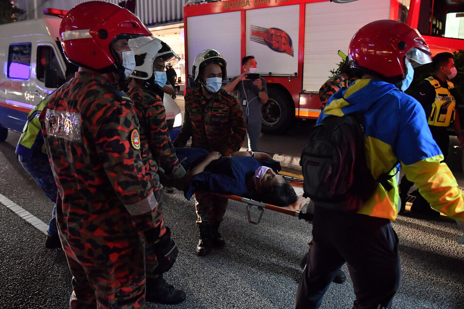Rettungskräfte tragen einen verletzten Fahrgast, nachdem zwei Light Rail Transit (LRT)-Züge in der Nähe der Station Kampung Baru zusammengestoßen sind.