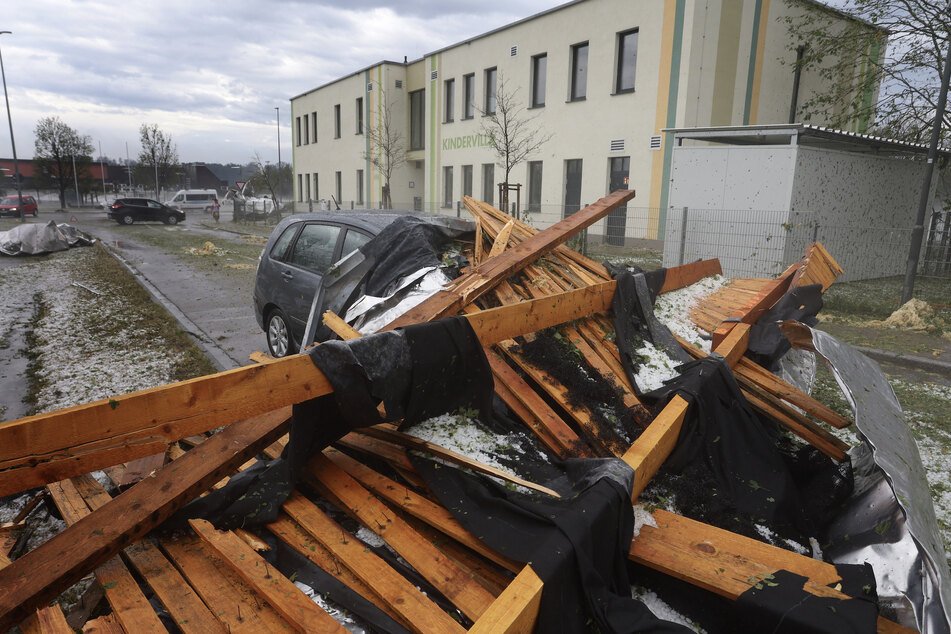 Ein vom Sturm abgetragenes Dach eines Seniorenheims in Kissing liegt auf einem Parkplatz auf einem Auto.