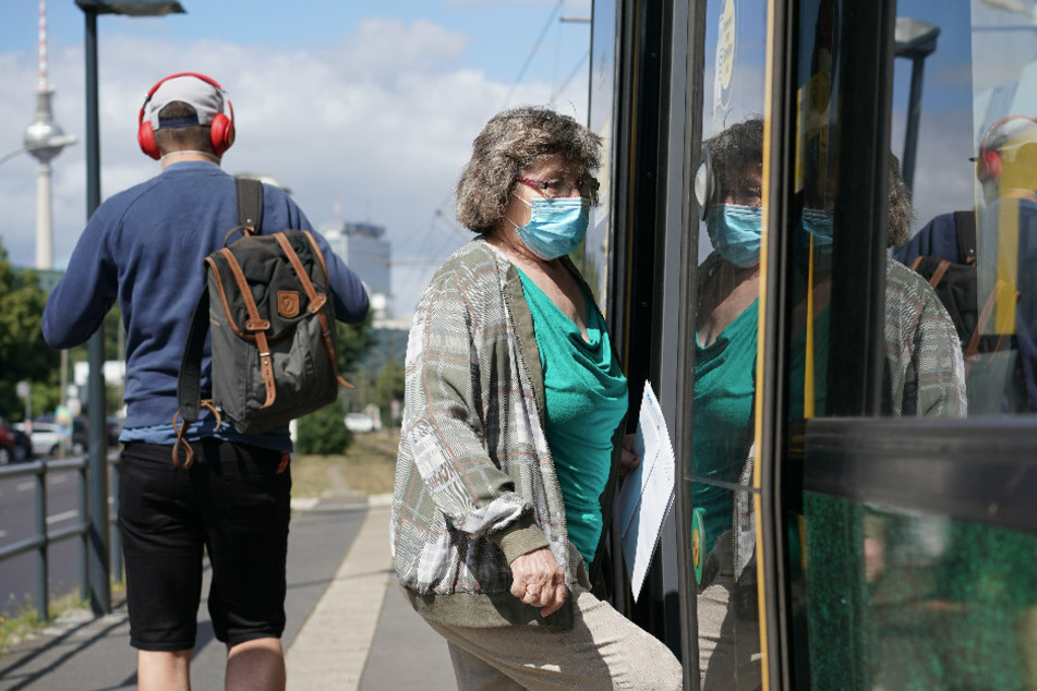 Eine Frau mit Mundschutz steigt an einem Bahnsteig in eine Tram. Ab sofort kontrollieren die Berliner Verkehrsbetriebe (BVG) die Maskenpflicht selbst.