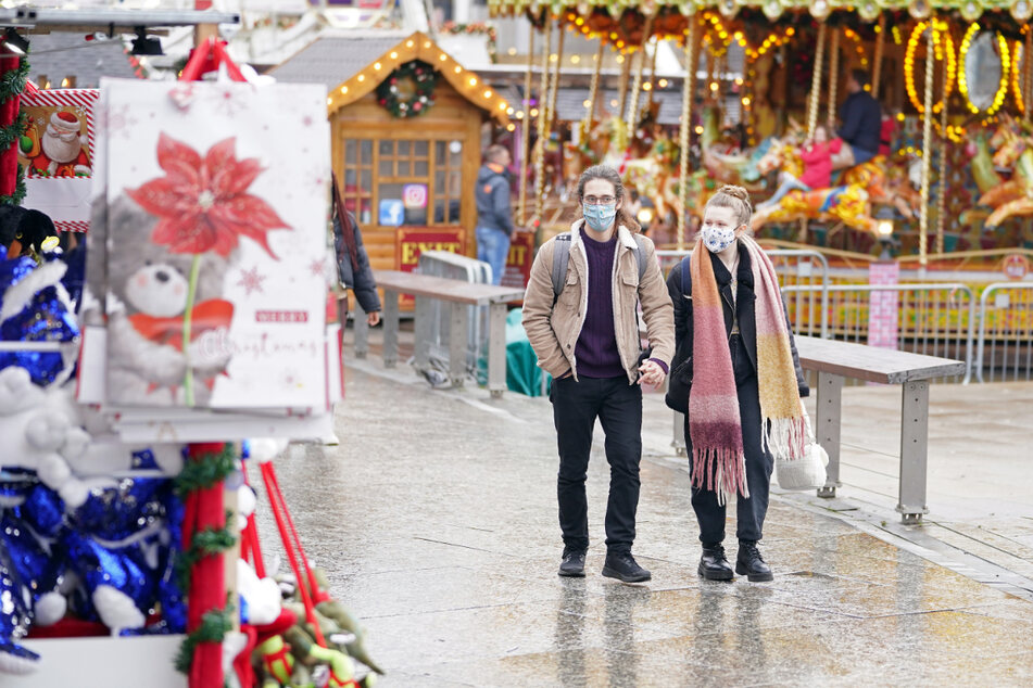 Ein Paar schlendert über einen Weihnachtsmarkt im Stadtzentrum.