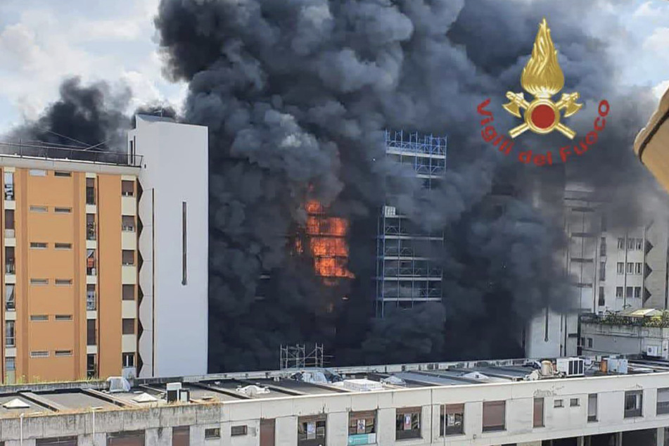 Ein riesige schwarze Rauchsäule stieg von dem brennenden mehrstöckigen Gebäude aus empor.