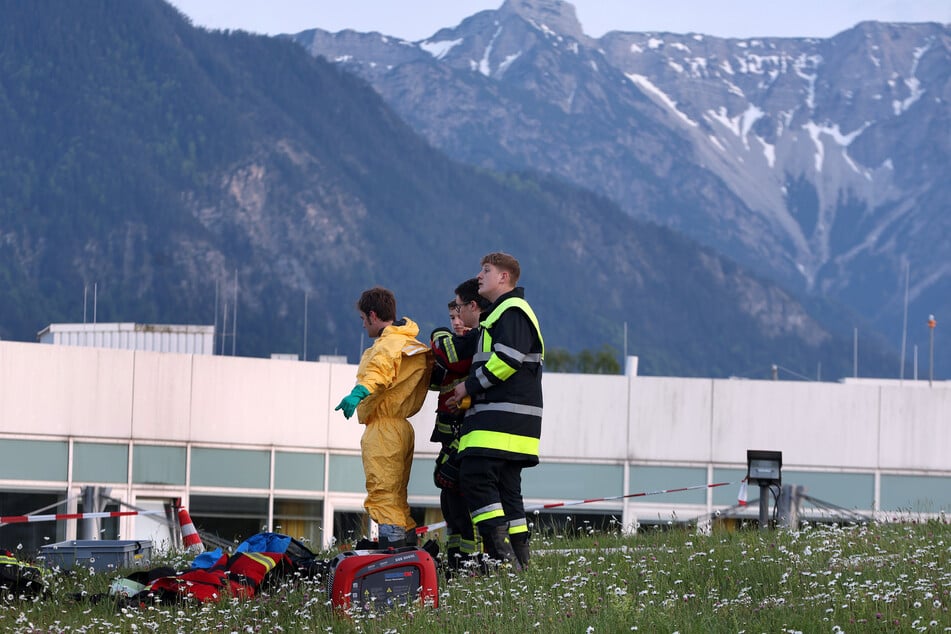 Einsatzkräfte ziehen vor der Klinik spezielle Schutzanzüge an.