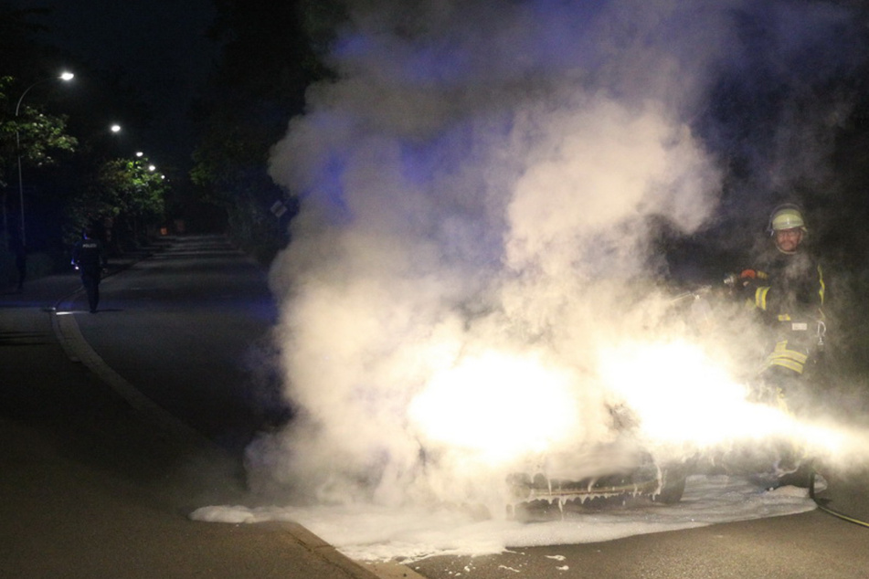 Ein Feuerwehrmann steht neben dem qualmenden Ford.