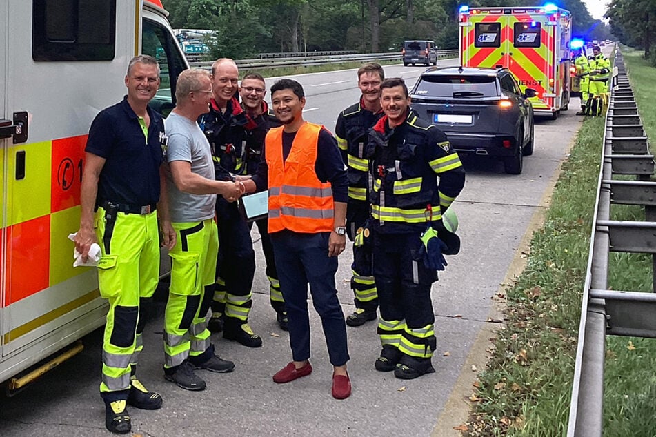Da freuen sich Papa (orange Weste) und die Rettungskräfte: Bei der spontanen Geburt auf der A95 scheint für Mama und Kind alles gut gelaufen zu sein.