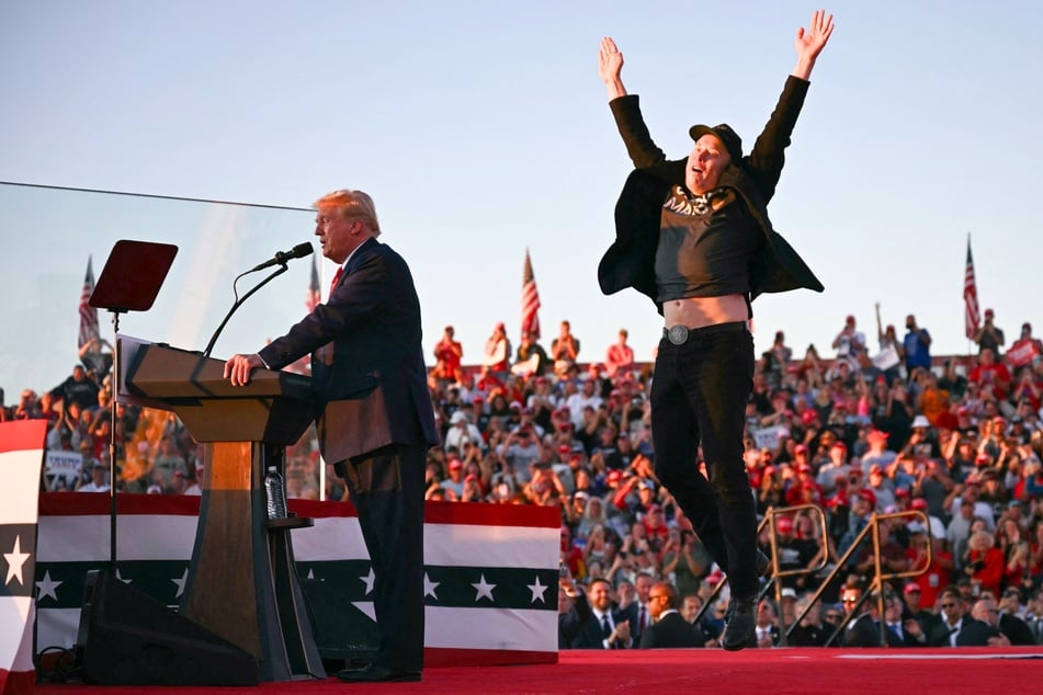 Elon Musk (r.) jumping on stage as he joins presidential candidate Donald Trump during a campaign rally in Butler, Pennsylvania on October 5, 2024.