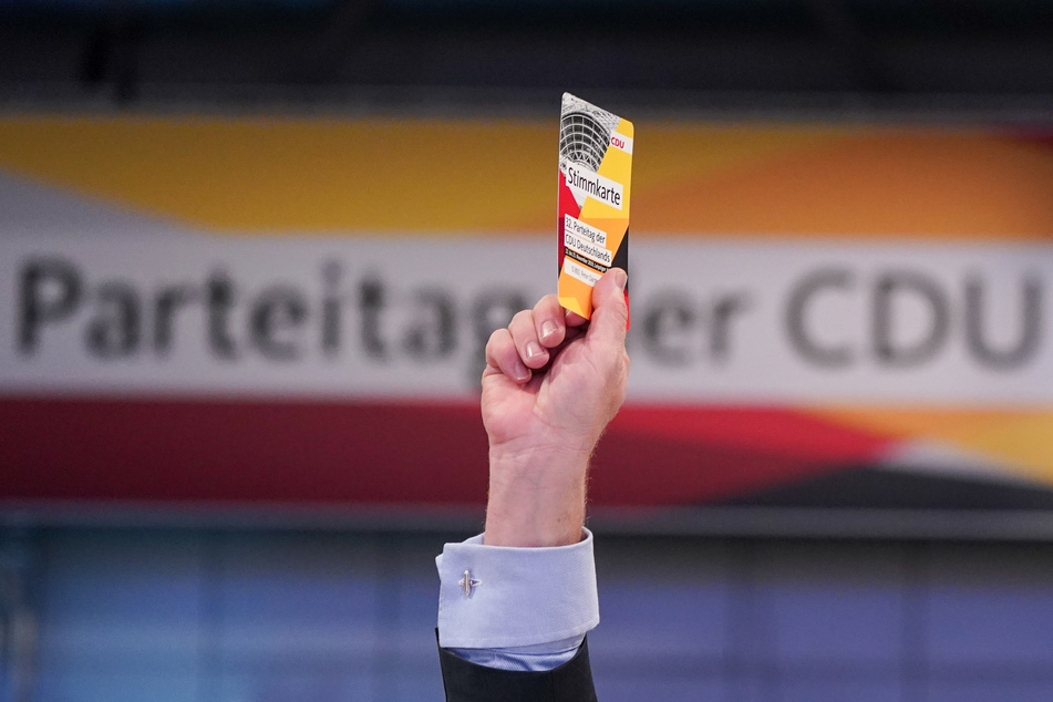 Ein Delegierter hält beim 32. CDU-Bundesparteitag seine Stimmkarte hoch.