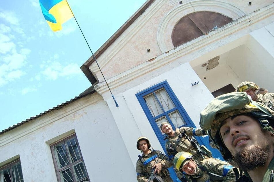Ukrainian soldiers pose with their national flag in the liberated village of Vasylenkove, in the Kharkiv region.