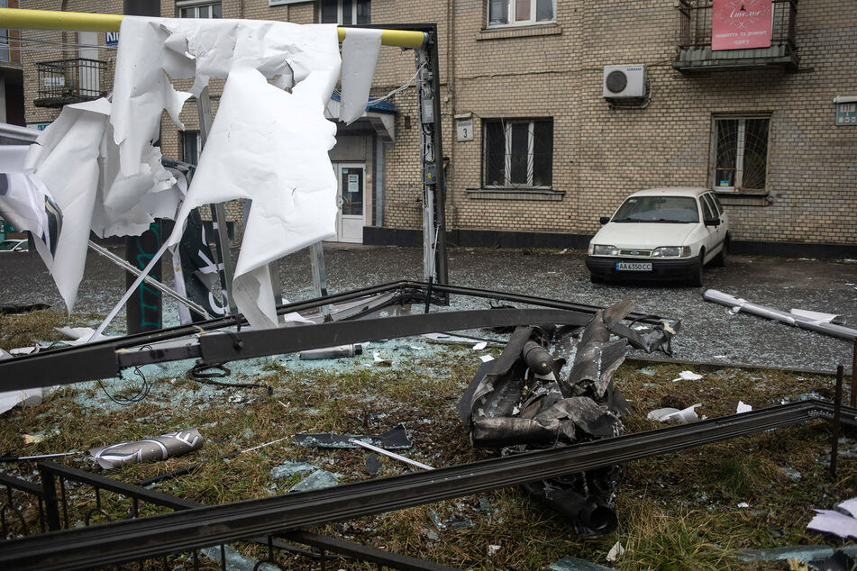 Police and security personnel inspect the remains of a shell on a street in Kyiv.