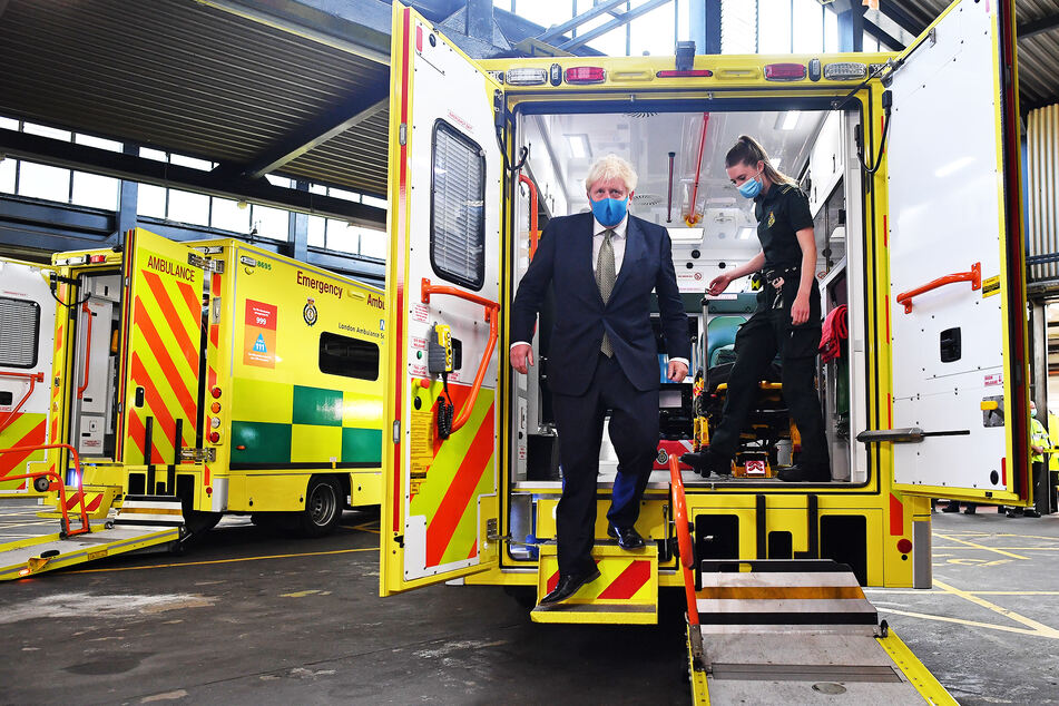 Boris Johnson, Premierminister von Großbritannien, trägt eine Stoff-Maske und steigt während eines Besuchs im Hauptquartier des London Ambulance Service NHS Trust mit einer Sanitäterin aus einem Krankenwagen.