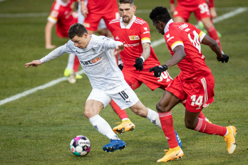 Stefan Lainer (v.l.n.r.) von Borussia Mönchengladbach kämpft gegen Berlins Robert Andrich (M.) und Taiwo Awoniyi (r.) um den Ball.