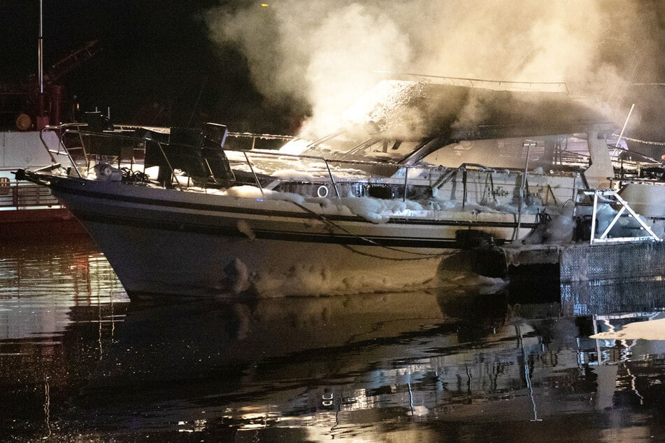 Das Foto zeigt das qualmende Wrack der Yacht im Sportboothafen in Frankfurt-Griesheim.
