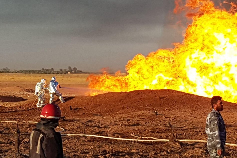 Feuerwehrleute löschen die Flammen einer Gas-Pipeline, die von einer Explosion zwischen Adra und Dumair getroffen wurde.