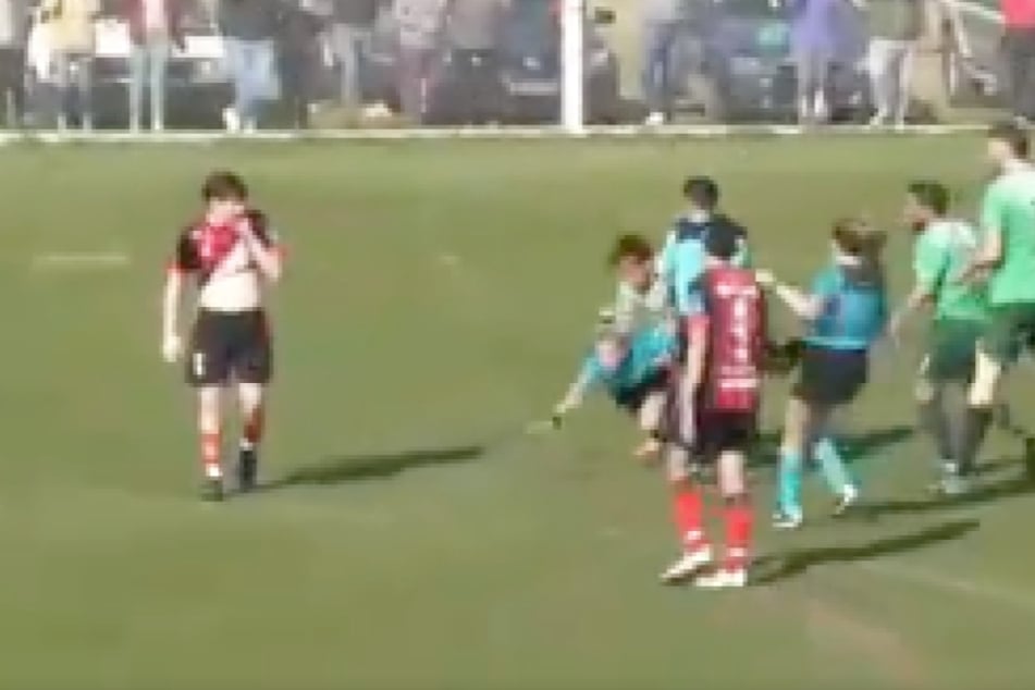 Die Schiedsrichterin wird in diesem Moment vom Angreifer brutal zu Boden gestoßen.