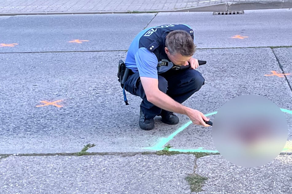 Nach dem Zusammenstoß von einer Siebenjährigen und einer Volvo-Fahrerin (56) in Berlin-Hellersdorf untersucht ein Polizist die Blutspur auf der Straße.