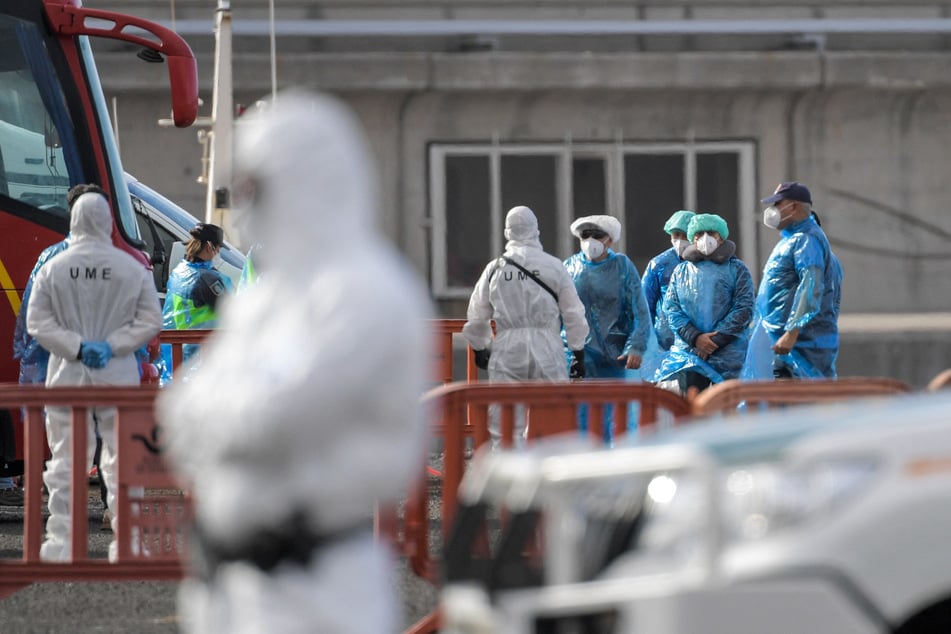 Passengers wearing a blue protective suits board a military bus after being evacuated from the hantavirus-stricken cruise ship MV Hondius at the industrial port of Granadilla de Abona on the island of Tenerife in Spain's Canary Islands on May 10, 2026.