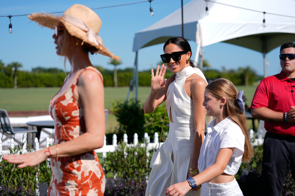 Meghan Markle waves to the press as she arrives at the Royal Salute Polo Challenge.
