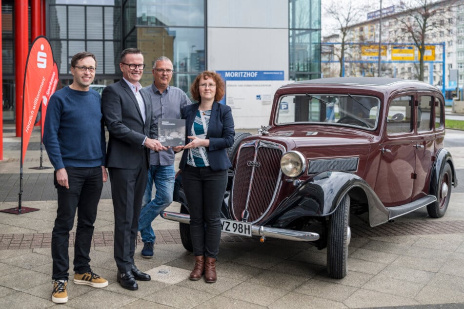 Kathy Eichholz (45, v.r.) und Ludwig Karsch (52) übergaben vor einer Wanderer-W26-Pullmann-Limousine ein Exemplar an Sparkassen-Vorstand Michael Kreuzkamp (56). Am Buch wirkte auch Jens Conrad (l.) mit.