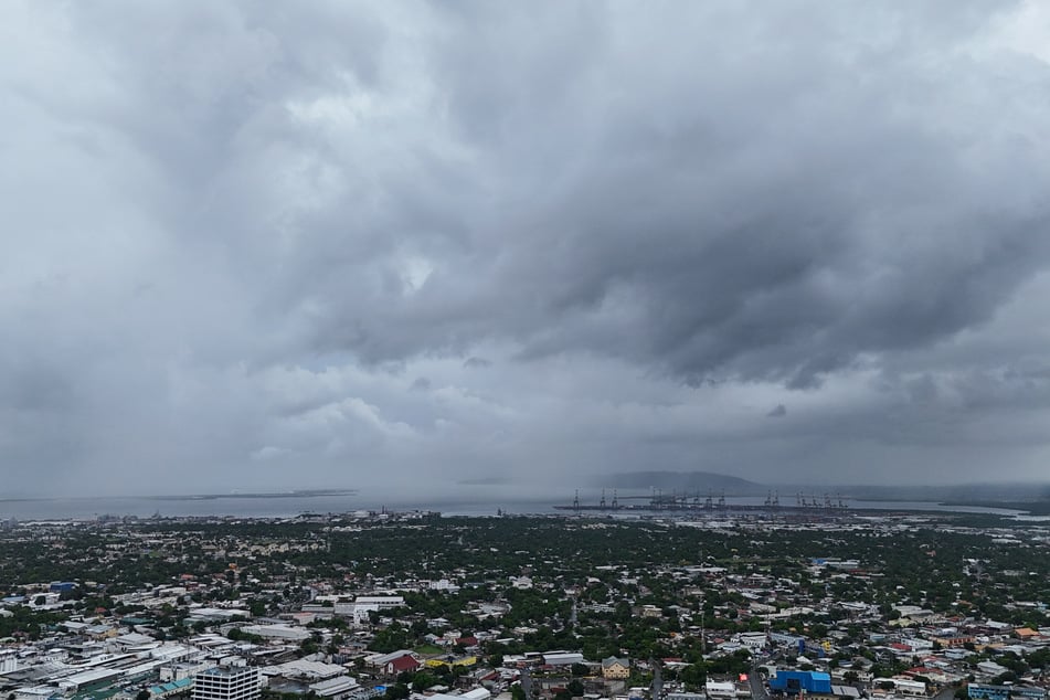 Una densa capa de nubes se cierne como un oscuro presagio sobre la capital jamaicana, Kingston. Los habitantes solo pueden rezar ahora para que la tormenta les spare la vida.