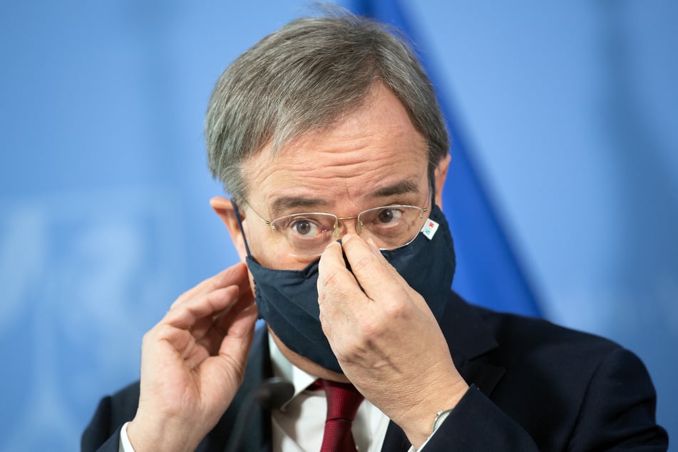 Armin Laschet (CDU), Ministerpräsident von Nordrhein-Westfalen, setzt nach einer Pressekonferenz seine Maske auf.