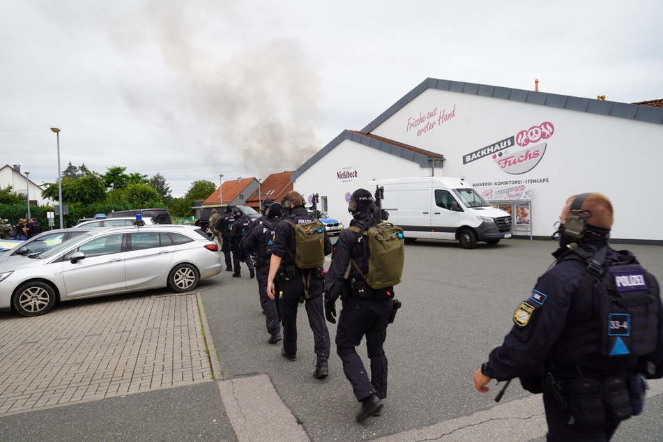 Einsatzkräfte laufen durch Altdorf. Im Hintergrund ist die Rauchsäule des Brandes zu erkennen.