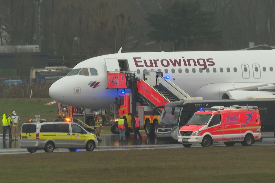Helfer stehen auf dem Flughafengelände an der betroffenen Eurowings-Maschine.