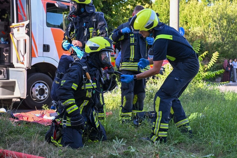 Die Einsatzkräfte setzen Atemschutzmasken auf.