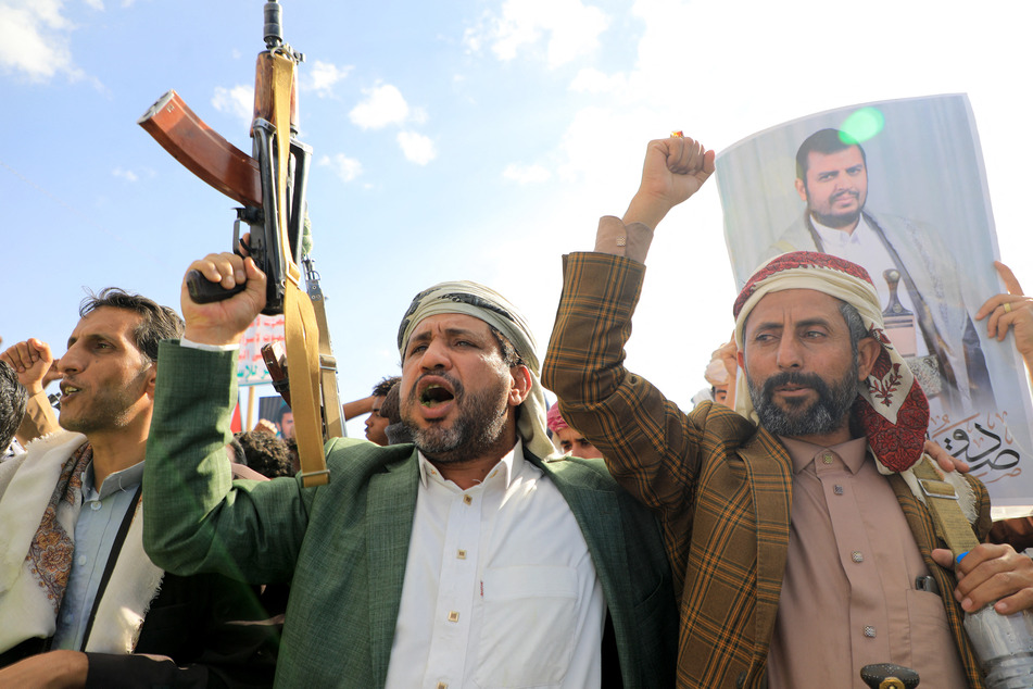 Yemeni men brandish their weapons and hold up portraits of Huthi leader Abdul Malik al-Houthi during a protest in solidarity with the Palestinian people in the Huthi-controlled Yemeni capital Sanaa on January 5, 2024.