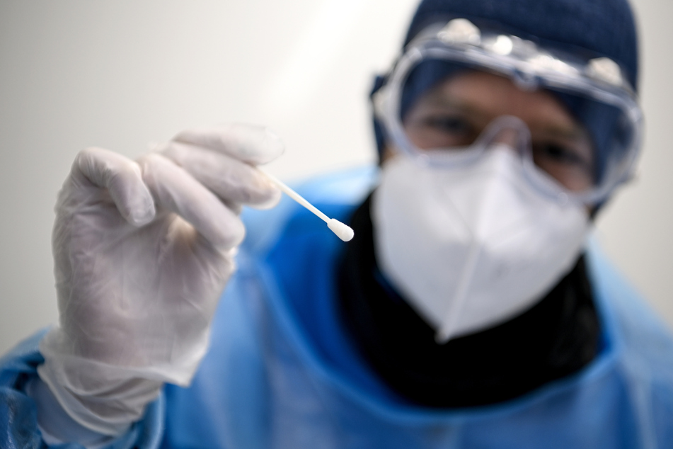 Ein Arzt hält ein Teststäbchen für die Entnahme einer Probe für einen PCR-Test beim Gesundheitsamt Neukölln in der Hand.