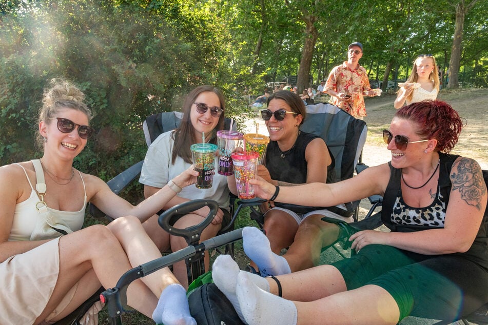 Marie (26, v.l.) Leonie (22), Cindy (32) und Elli (34) machen es sich auf der Treppe neben der Bühne mit Getränken bequem.